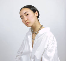 Load image into Gallery viewer, Model is sitting wearing a white oversized shirt and the dalia chain collar
